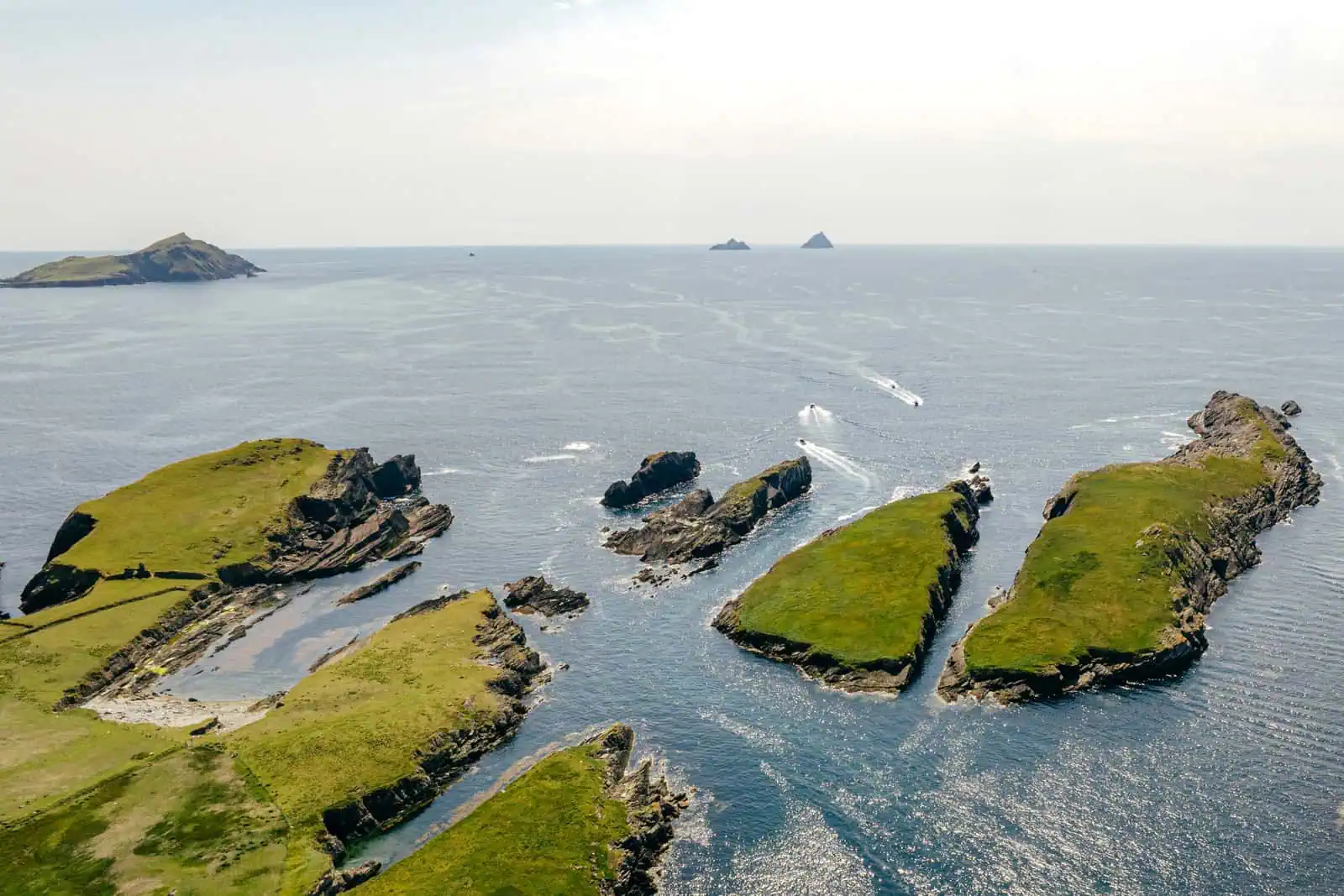 Aerial view of the Skellig Islands and boats, seen on a Skellig Michael boat tours from Portmagee. Rocky, grass-covered isles. 