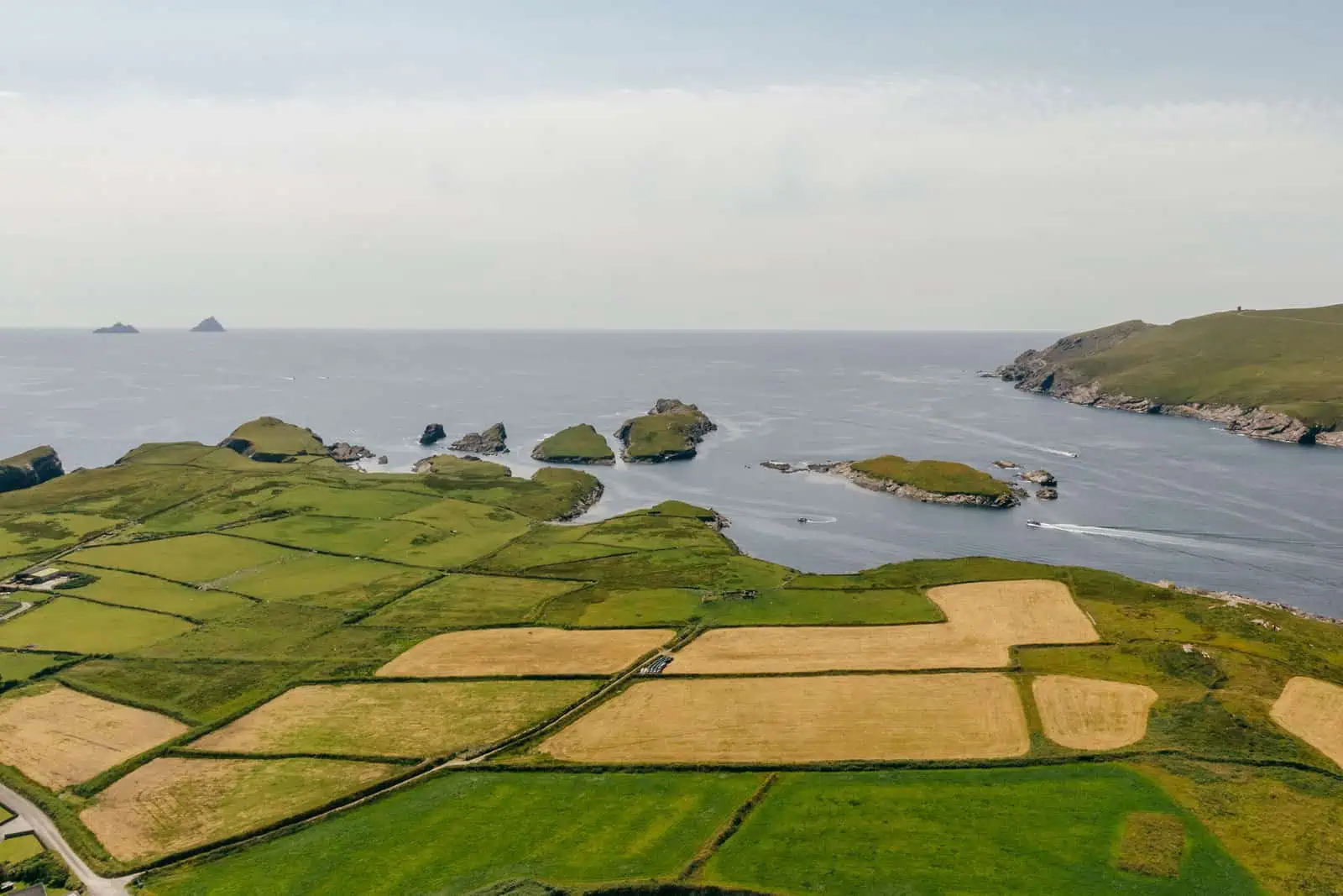 Aerial view of green Irish farmland, ocean, and Skellig Michael in the distance. Skellig Michael Landing Tour available. 