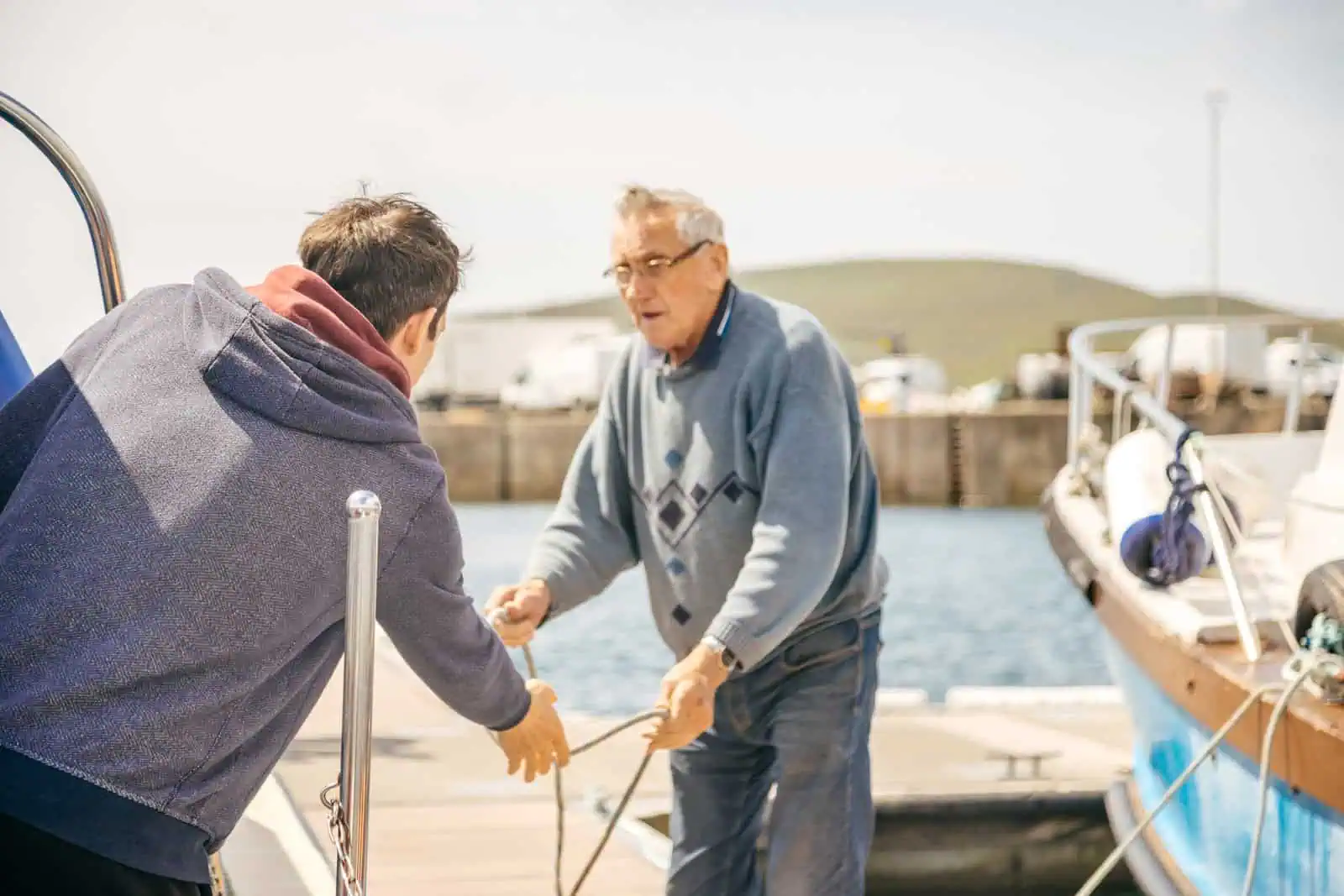 Two men handling mooring ropes on a boat, ready for Skellig Michael Tours from Portmagee. The harbour is in the background.