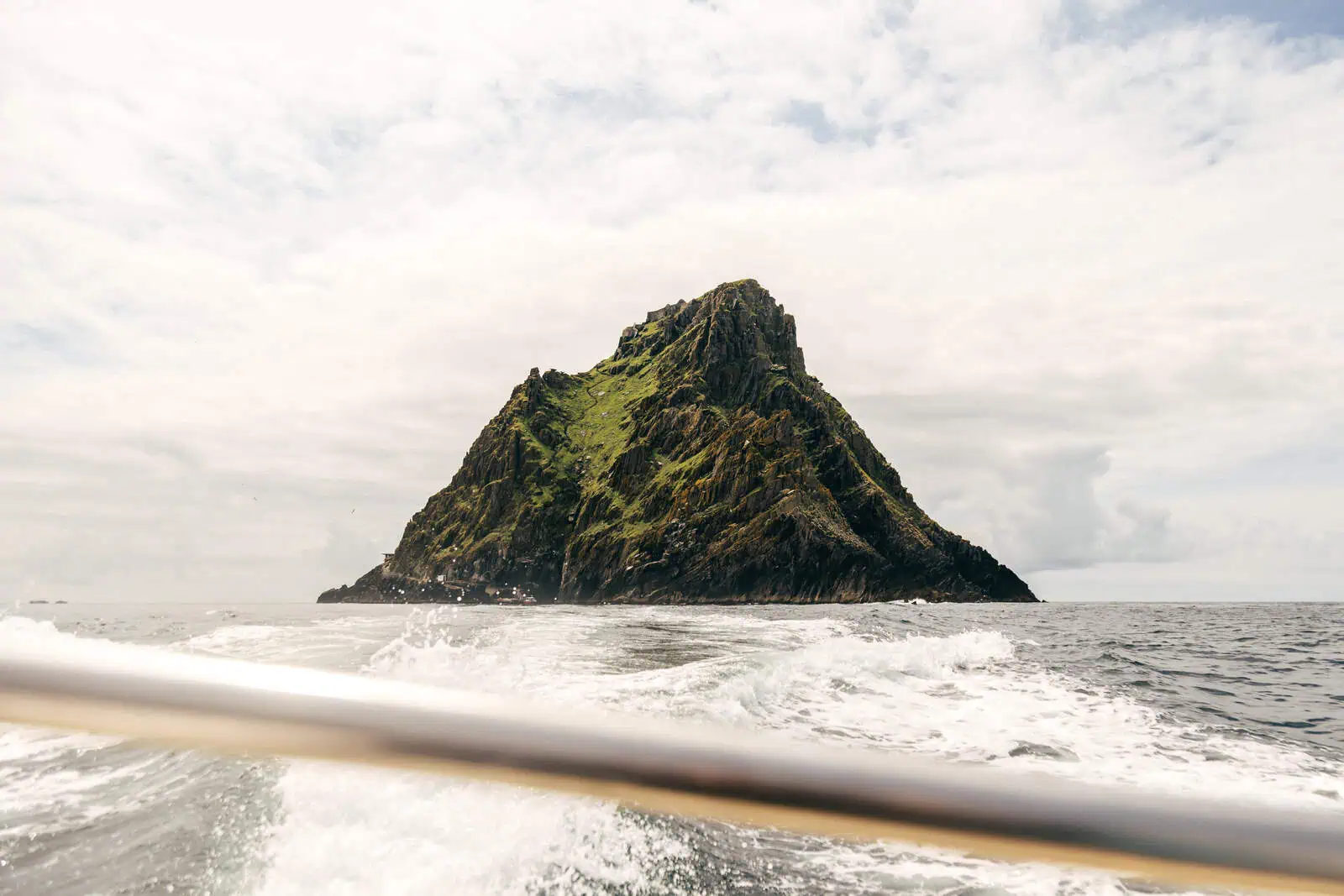 View of Skellig Michael, a rugged island, from a boat showing the wake. Book Skellig Michael boat tours for an unforgettable experience.