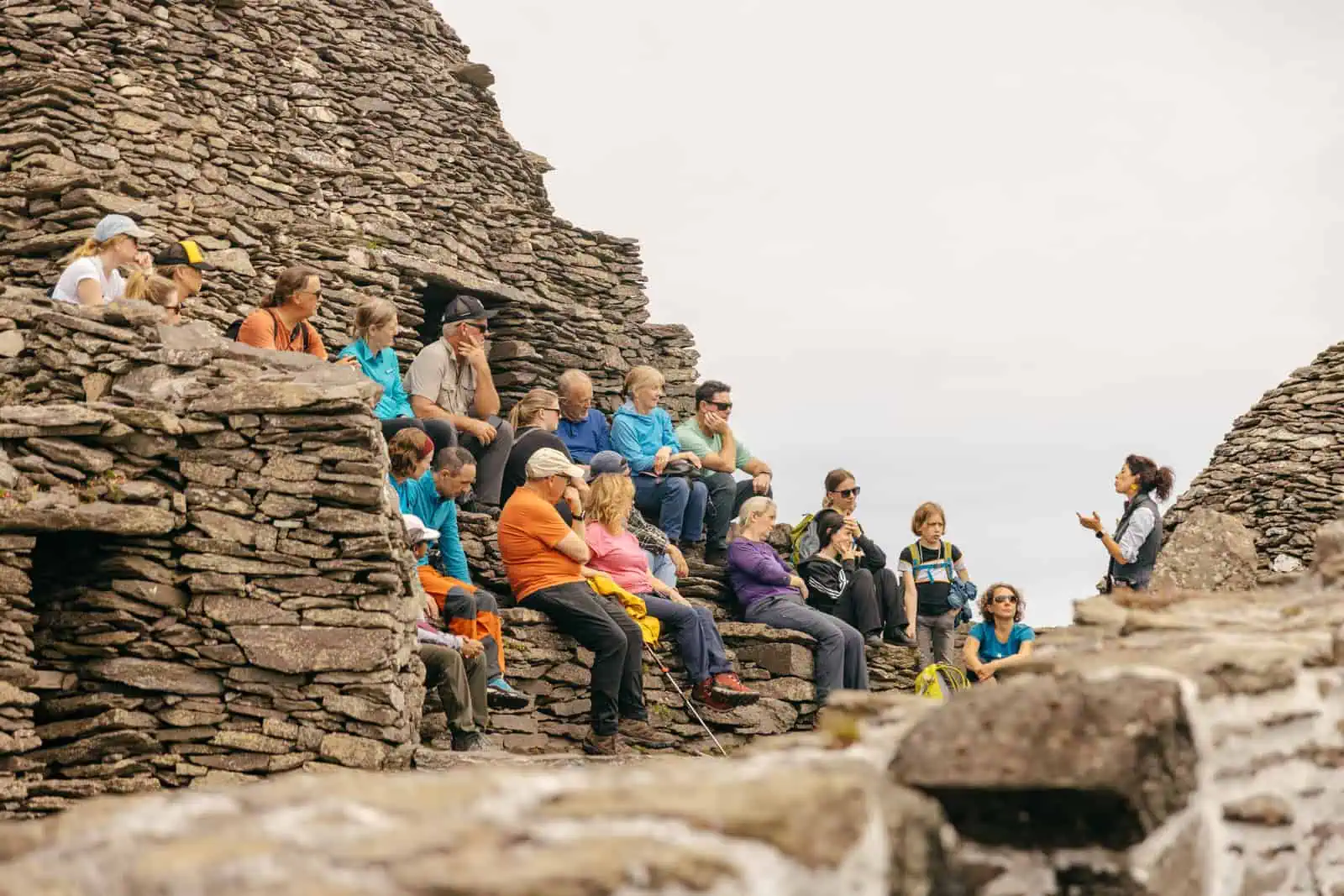A Skellig Michael tour group listens to a guide amidst the ancient stone structures on the island. 